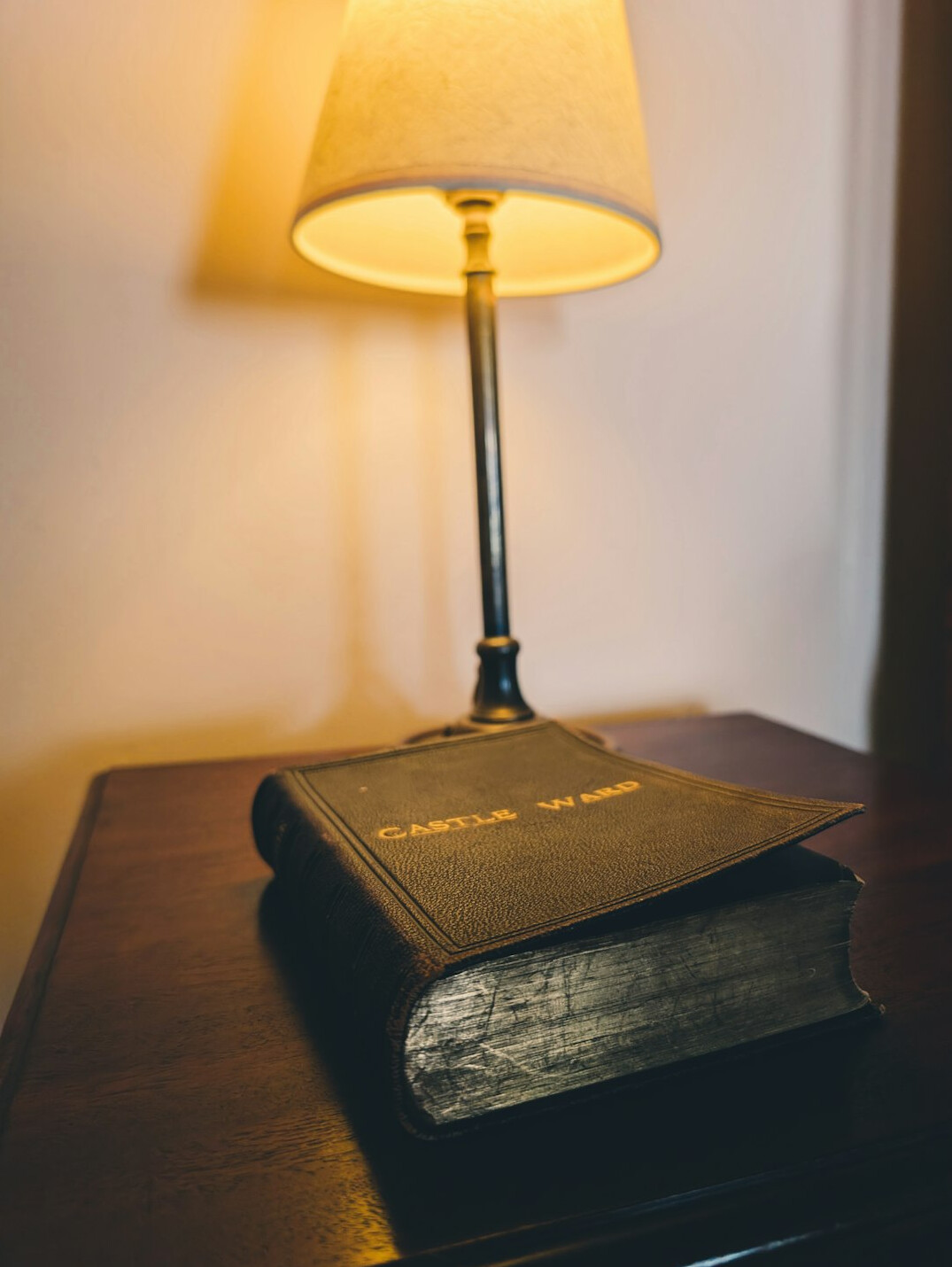 Stack of old hardcover books with a reading lamp