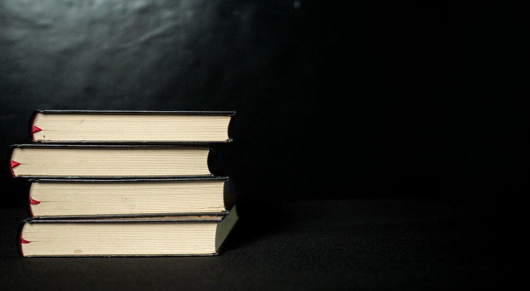 Stack of mystery novels on a dark wooden shelf