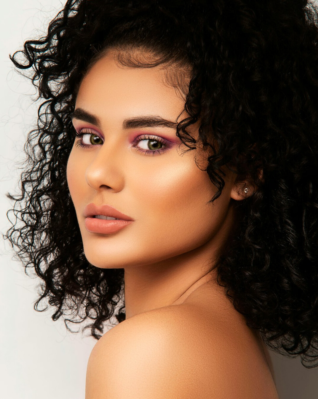 Studio portrait of a young Hispanic woman with curly hair